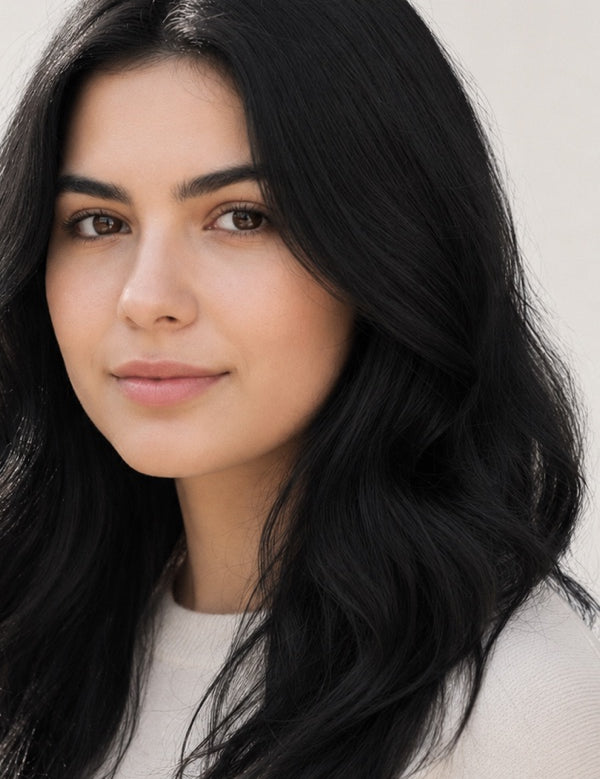 Woman modelling Radico Soft Black hair colour, with a centre part and glossy black hair falling in loose waves around her shoulders.