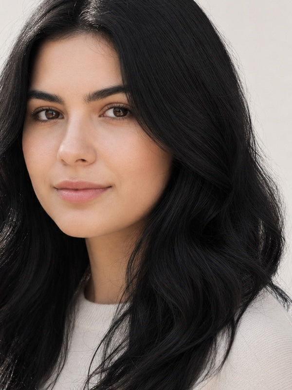 Woman modelling Radico Soft Black hair colour, with a centre part and glossy black hair falling in loose waves around her shoulders.