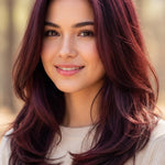 Smiling woman modelling Radico Wine Red hair colour, with glossy burgundy-red layers curving inward around her shoulders and brighter red highlights near the crown.
