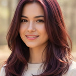Smiling woman with glossy burgundy-red layers curving inward around her shoulders, with a small label beneath identifying the shade as Wine Red.
