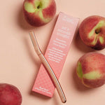 Clean Nectarine Reusable Metal Dermaplaner and pink packaging arranged with fresh nectarines.