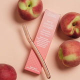 Clean Nectarine Reusable Metal Dermaplaner and pink packaging arranged with fresh nectarines.