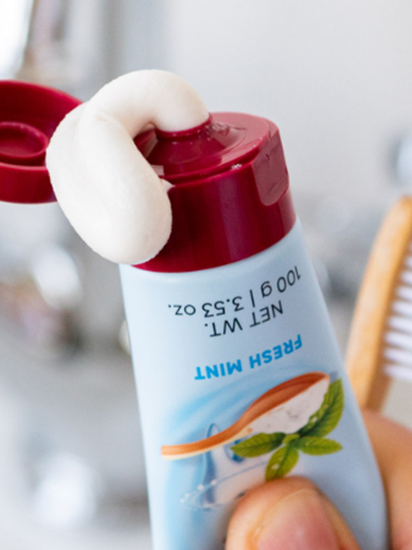 Red Seal Baking Soda Hydroxyapatite Toothpaste being squeezed beside a toothbrush