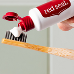 Red Seal Baking Soda Toothpaste being applied to a toothbrush