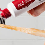 Red Seal Complete Care Toothpaste being applied to a toothbrush