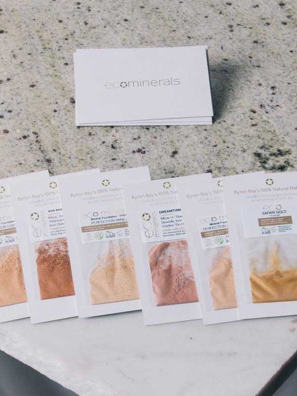 Eco Minerals Flawless Matte Mineral Foundation 5g is shown in six sample shades on a light countertop, with a white Eco Minerals box behind them. Enjoy natural matte finish and gentle daily coverage.