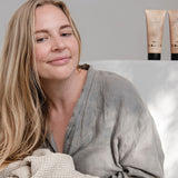 Woman in a grey robe holding a textured towel beside Sanctum Everyday Conditioner and matching haircare tubes.