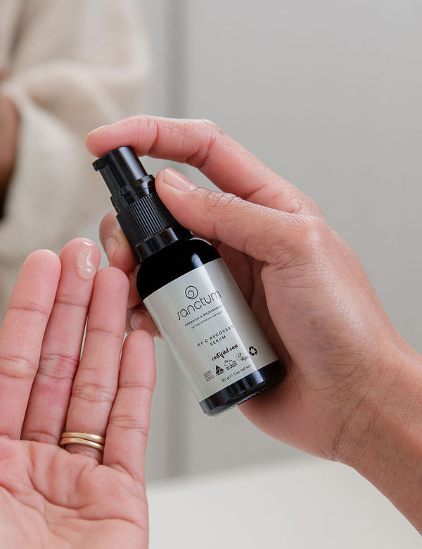 Sanctum HY C Recovery Serum being pumped from the bottle into an open palm.