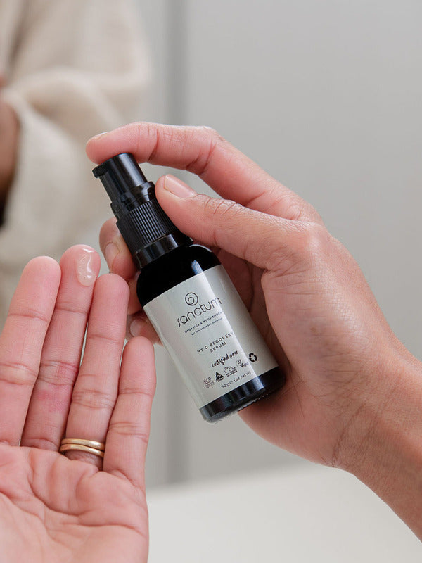 Sanctum HY C Recovery Serum being pumped from the bottle into an open palm.