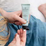 Sanctum Night Conditioning Cream tube held during a relaxing bedtime skincare routine.