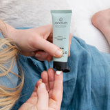 Sanctum Night Conditioning Cream tube held during a relaxing bedtime skincare routine.