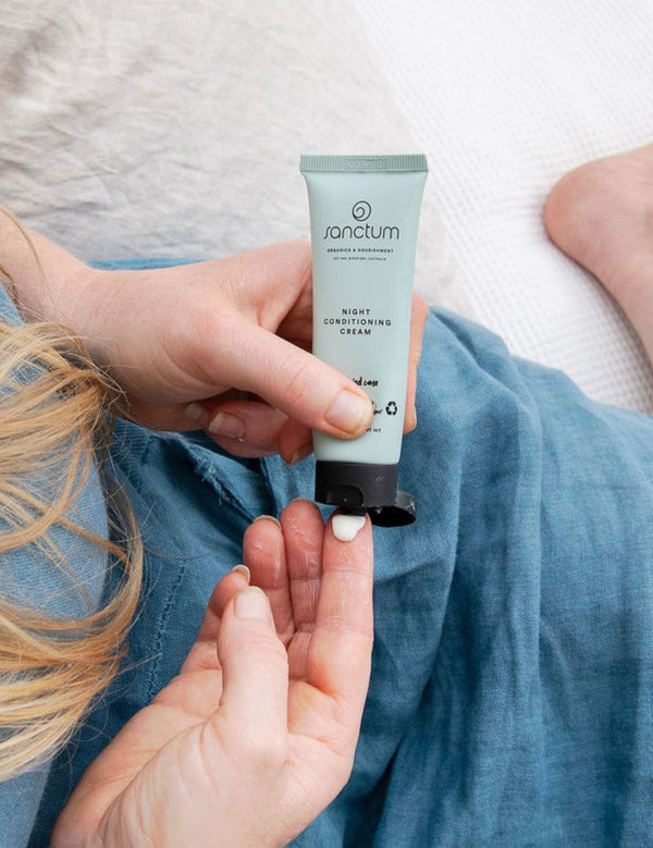 Sanctum Night Conditioning Cream tube held during a relaxing bedtime skincare routine.