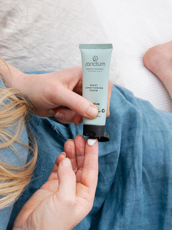 Sanctum Night Conditioning Cream tube held during a relaxing bedtime skincare routine.