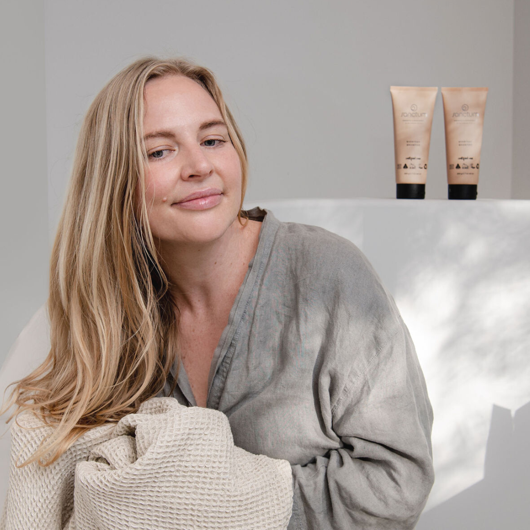 Woman holding towels beside Sanctum Everyday Conditioner