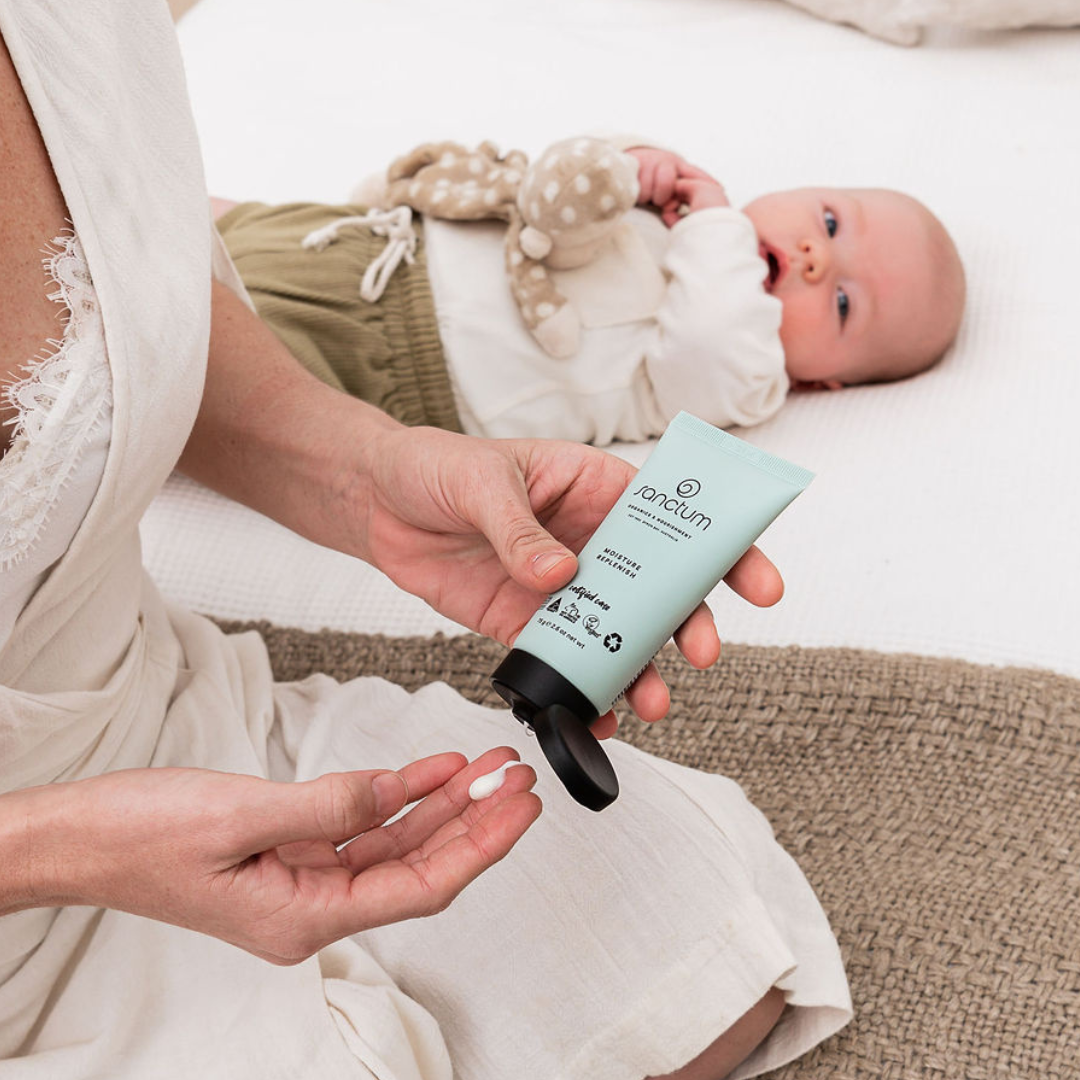 Parent using Sanctum Moisture Replenish beside a baby