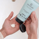 Hands dispensing Sanctum Soothing Cream Cleanser from the tube during a skincare routine.