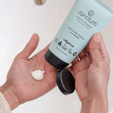 Hands dispensing Sanctum Soothing Cream Cleanser from the tube during a skincare routine.