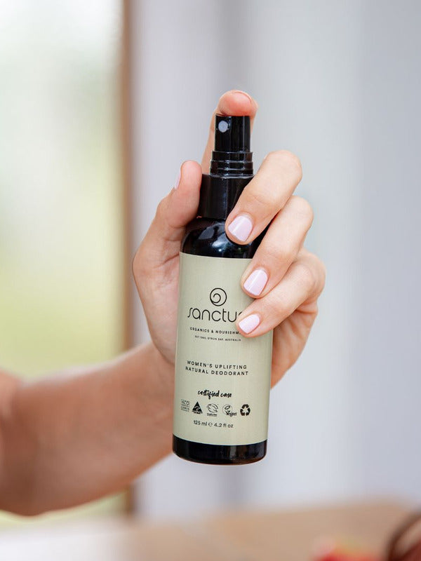 Hand holding Sanctum Women's Deodorant Spray upright with the front label facing the camera.