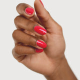 A medium-brown hand with fingers loosely curled to display rounded, glossy coral-red nails painted in Sienna Byron Bay Dance.