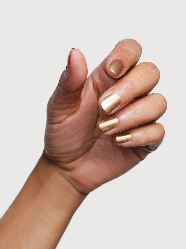 Hand modelling Sienna Byron Bay Divine nail polish, a luminous champagne-gold metallic shade.