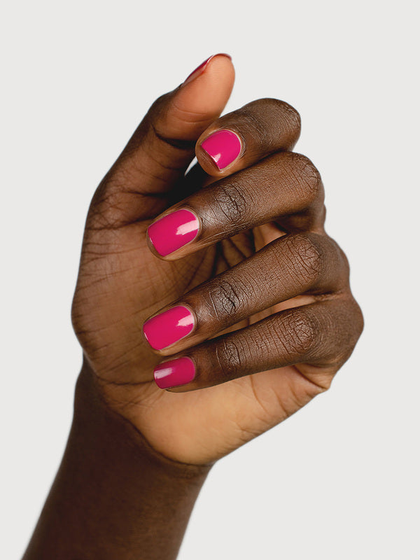 A deep-brown hand with fingers loosely curled to display glossy raspberry-pink nails painted in Sienna Byron Bay Goddess.