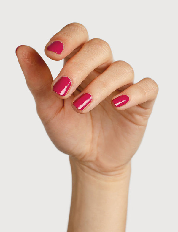 A light-skinned hand with fingers loosely curled to display glossy raspberry-pink nails painted in Sienna Byron Bay Goddess.