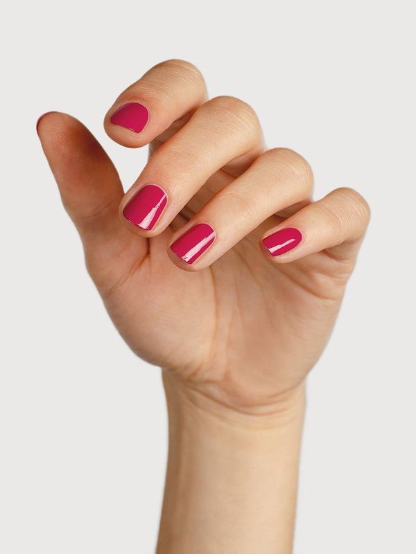 A light-skinned hand with fingers loosely curled to display glossy raspberry-pink nails painted in Sienna Byron Bay Goddess.