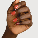A deep-brown hand with fingers loosely curled to display glossy terracotta-red nails painted in Sienna Byron Bay Life.