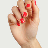 Close-up of a hand wearing Sienna Byron Bay Kiss nail polish in a vivid coral-red shade.