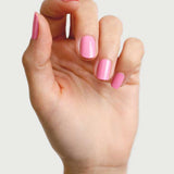 A hand with neatly manicured nails painted in Sienna Byron Bay Nail Polish - Magnolia, a glossy, plant-derived pink shade, shown against a plain light background.