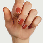 Hand displaying neatly manicured nails painted in the glossy terracotta Courage shade by Sienna Byron Bay.