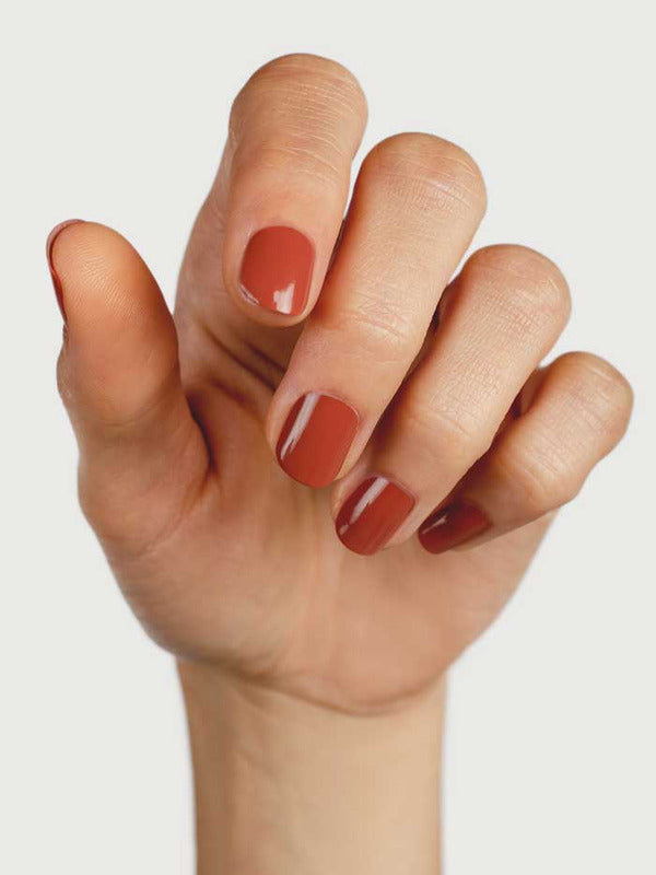 Hand displaying neatly manicured nails painted in the glossy terracotta Courage shade by Sienna Byron Bay.