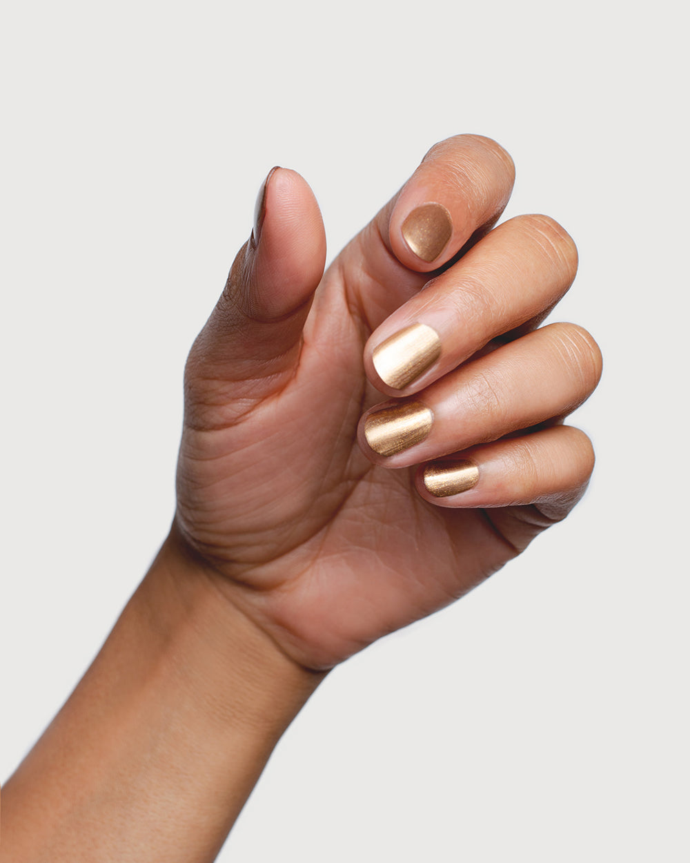 Sienna Divine gold nail polish shown on medium skin tone