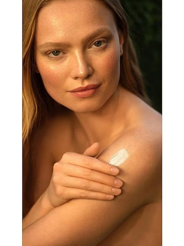 Woman applying the rich texture of Weleda Skin Food Body Butter to her shoulder