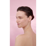 Woman's profile with Smoothing Wild Rose & White Tea cream on her face in a pink background.