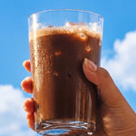 Sodii Everyday Hydration Salts Salty Chocolate iced chocolate held against a blue sky