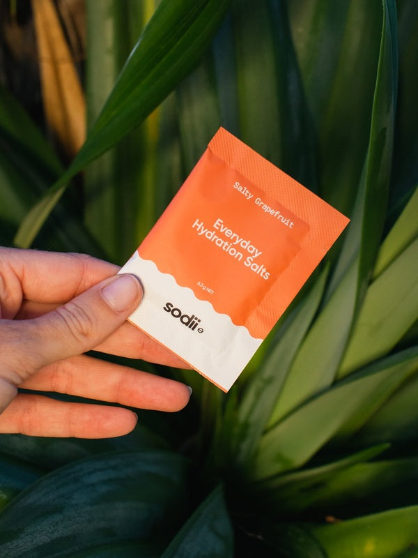 Sodii Everyday Hydration Salts Salty Grapefruit held against tropical greenery