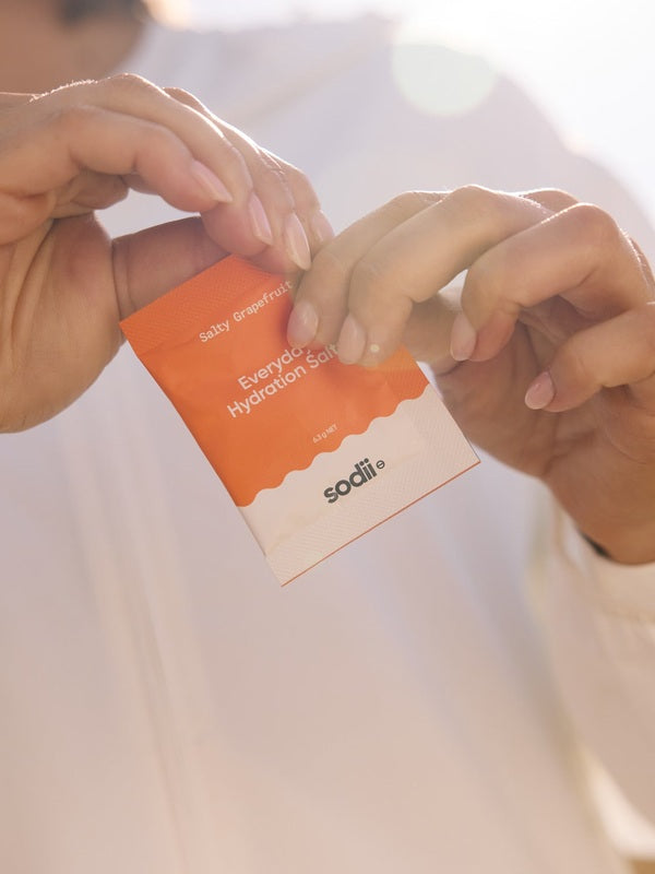 Sodii Everyday Hydration Salts Salty Grapefruit sachet being opened in bright sunlight