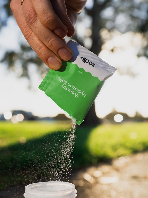 Sodii Everyday Hydration Salts Salty Kiwi being poured into a bottle outdoors