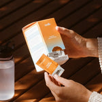 Sodii Everyday Hydration Salts Salty Mandarin box being opened beside a water bottle