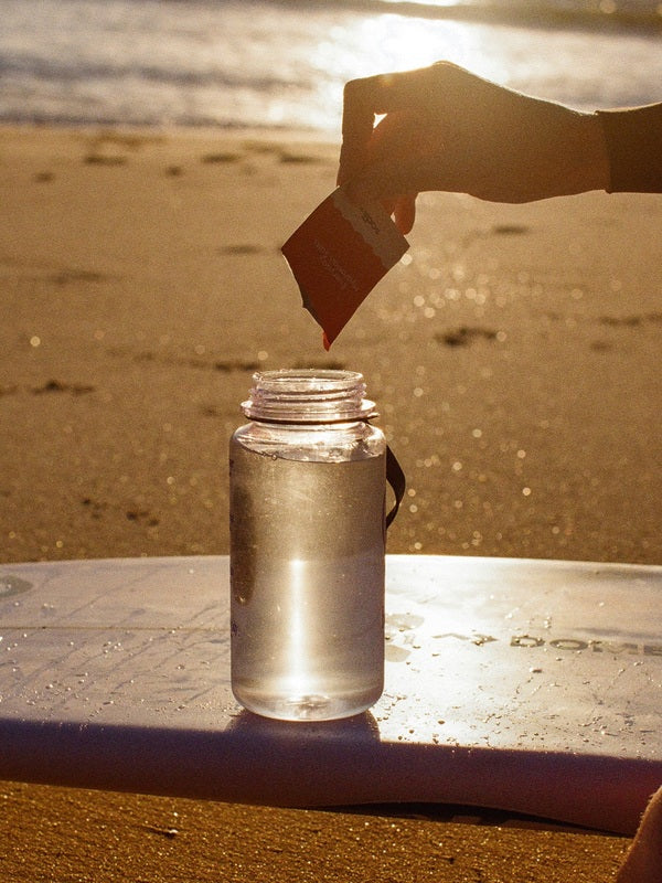 Sodii Everyday Hydration Salts Salty Mandarin being mixed into a bottle at sunset