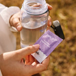Sodii Everyday Hydration Salts Salty Passionfruit held with a water bottle outdoors
