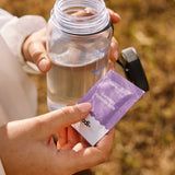 Sodii Everyday Hydration Salts Salty Passionfruit held with a water bottle outdoors