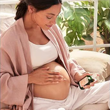 Pregnant woman applying Weleda Stretch Mark Massage Oil to her belly.