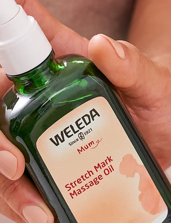 Weleda Stretch Mark Massage Oil bottle held in hand.