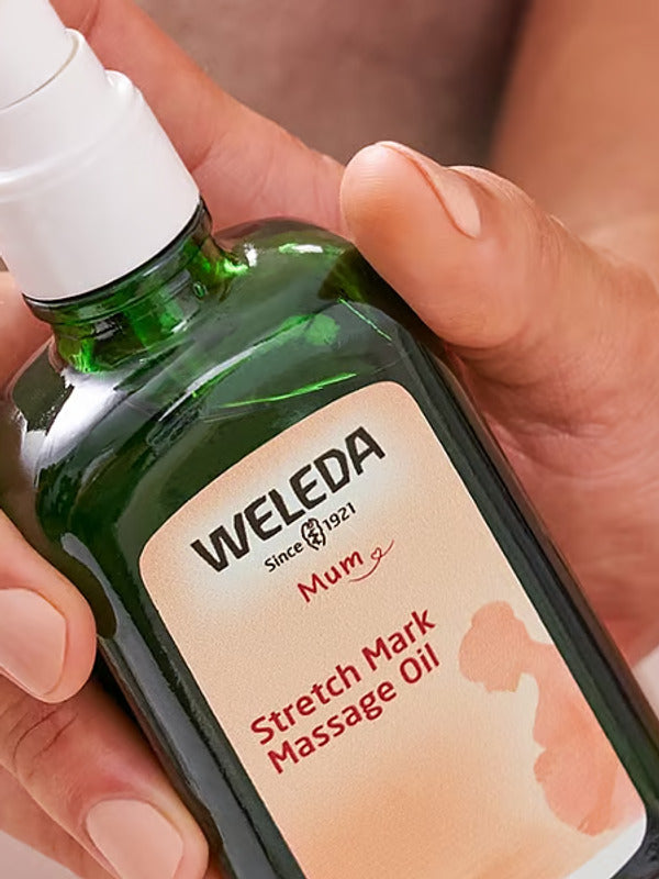 Weleda Stretch Mark Massage Oil bottle held in hand.