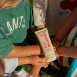 Children outdoors placing their hands together beneath a tube of Sun & Daughter SPF50 Mineral Sunscreen for Babies and Children.