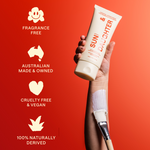 A hand holds the ivory Sun & Daughter mineral sunscreen tube against a red and coral background, beside icons labelled fragrance free, Australian made and owned, cruelty free and vegan, and 100% naturally derived.