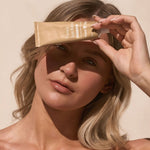 Woman holding Tinted Sun Balm in sunlight – Thrive Tallow Tinted Sun Balm with Zinc 70ml