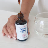 Fulvic Humic Concentrate dropper being used beside a glass of water